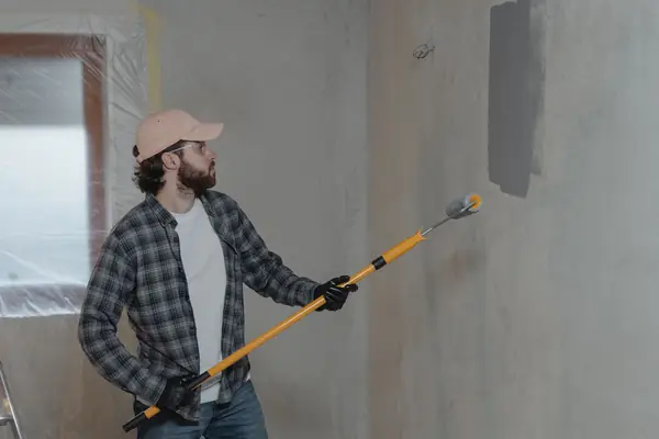 Painter rolling grey paint onto an interior wall in Baton Rouge